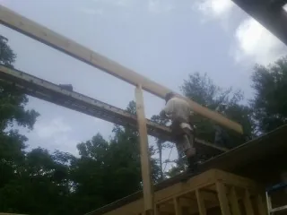 Carpenter setting a ridge beam over a new addition frame — Ice Dam Removal by Roofing Brothers in Centerport