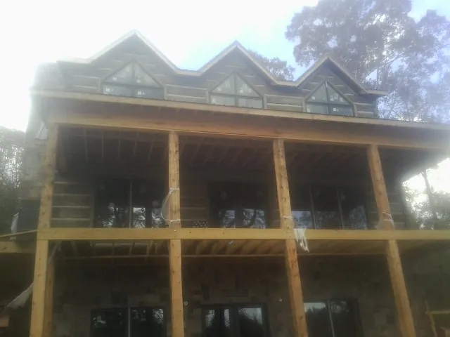 Dormers and porch framing on a large log home under construction — Roof Coating work by our crew in Centerport