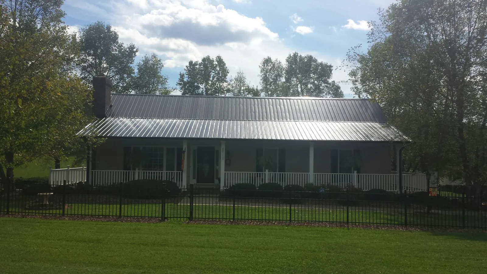 Gray metal roof on a brick ranch with a full width front porch — Gutter Guard Installation work by our crew in Centerport