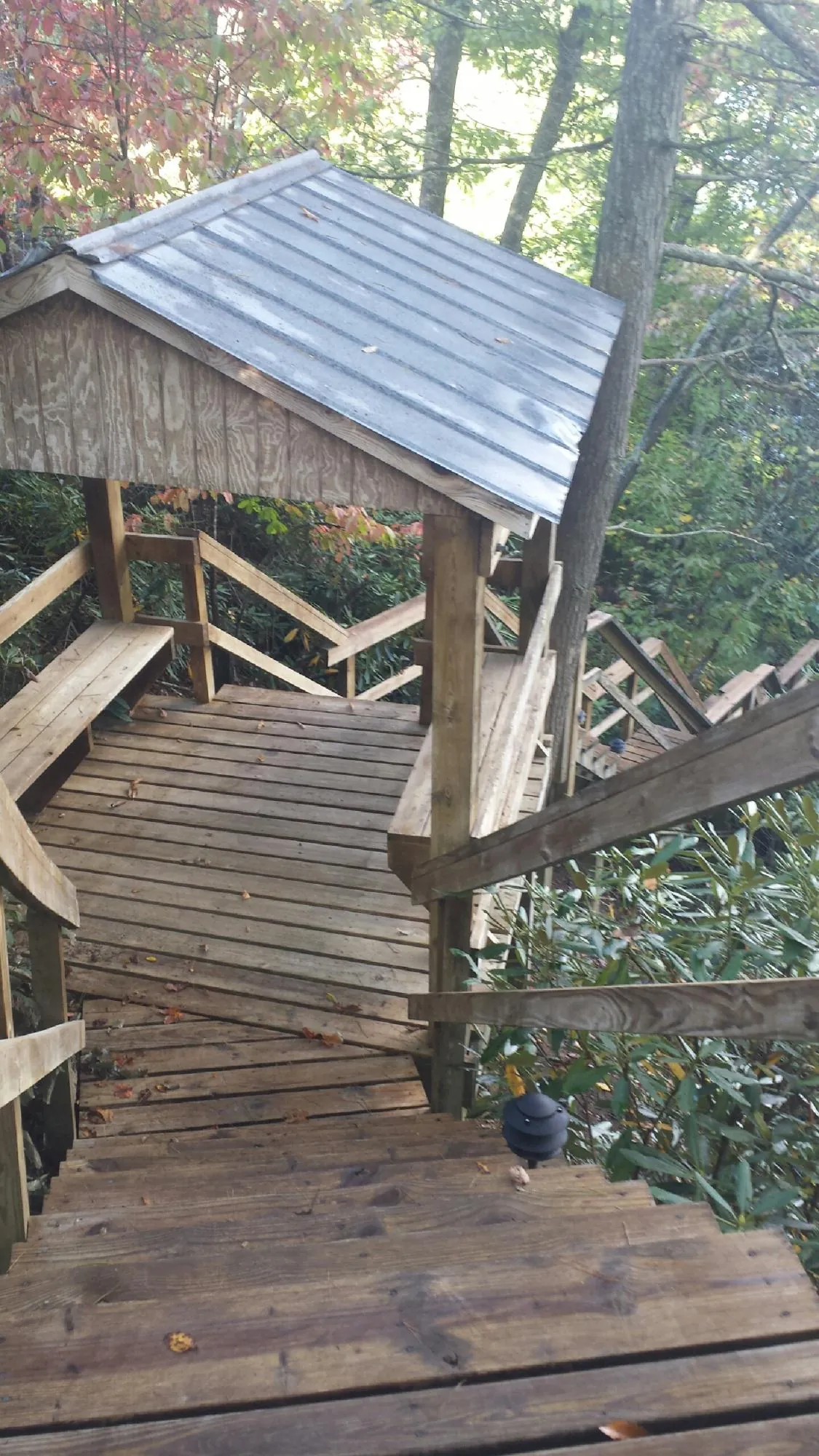 Metal roofed shelter over wooden steps on a wooded walkway — Skylight Repair & Installation work by our crew in Centerport