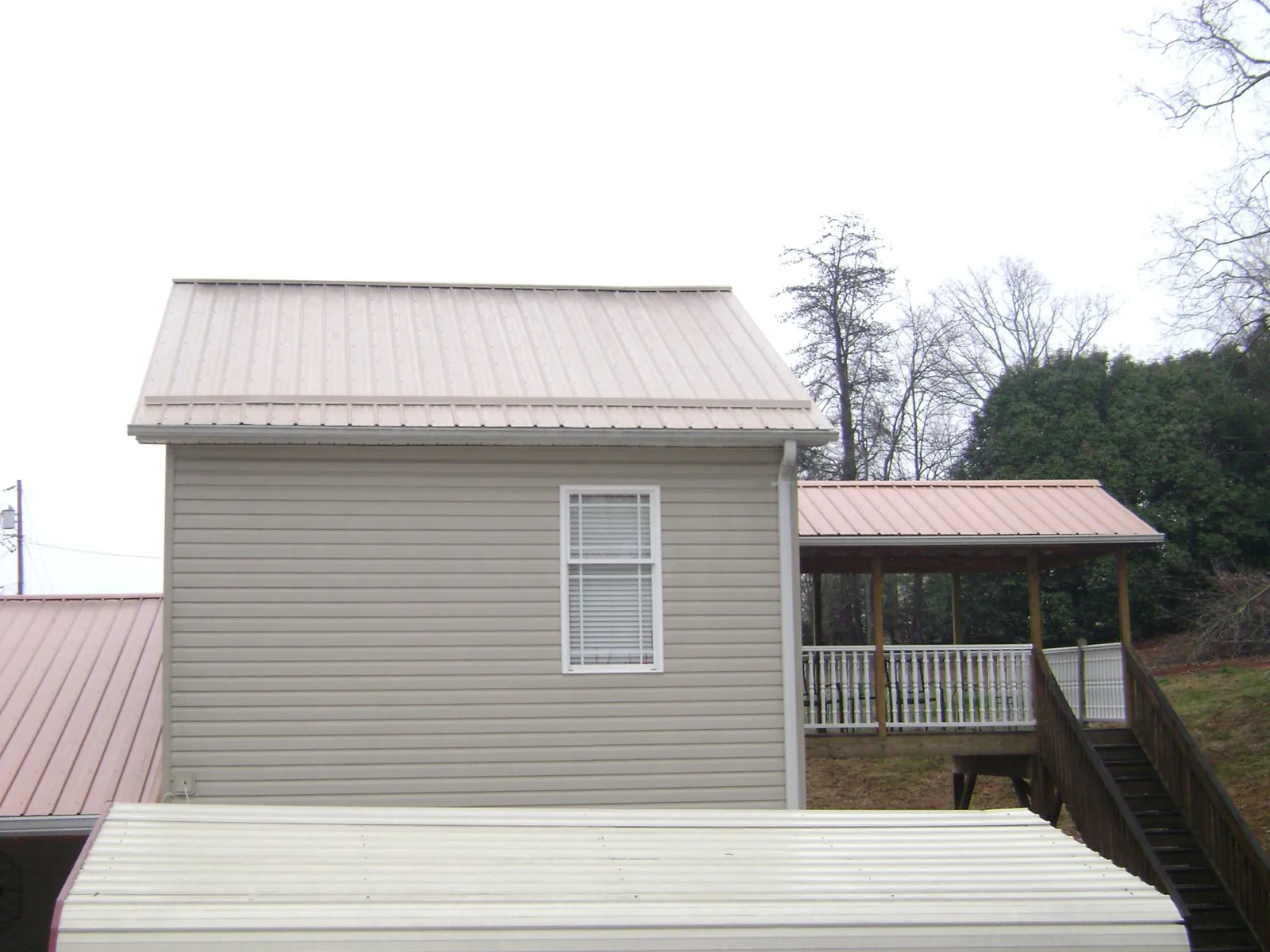 Tan metal roofs on a two story addition and attached porch, from a Roof Replacement job in Centerport