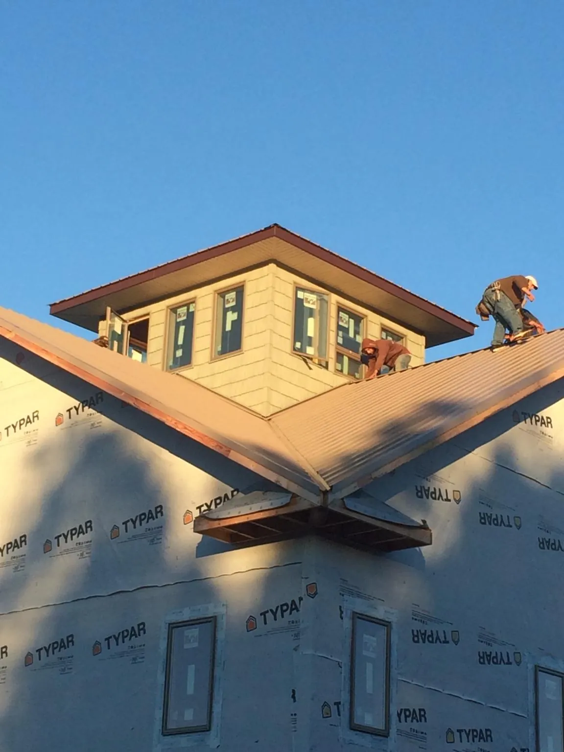 Roofers working around a rooftop cupola on a new metal roof at sunset — Roof Waterproofing in Centerport by Roofing Brothers